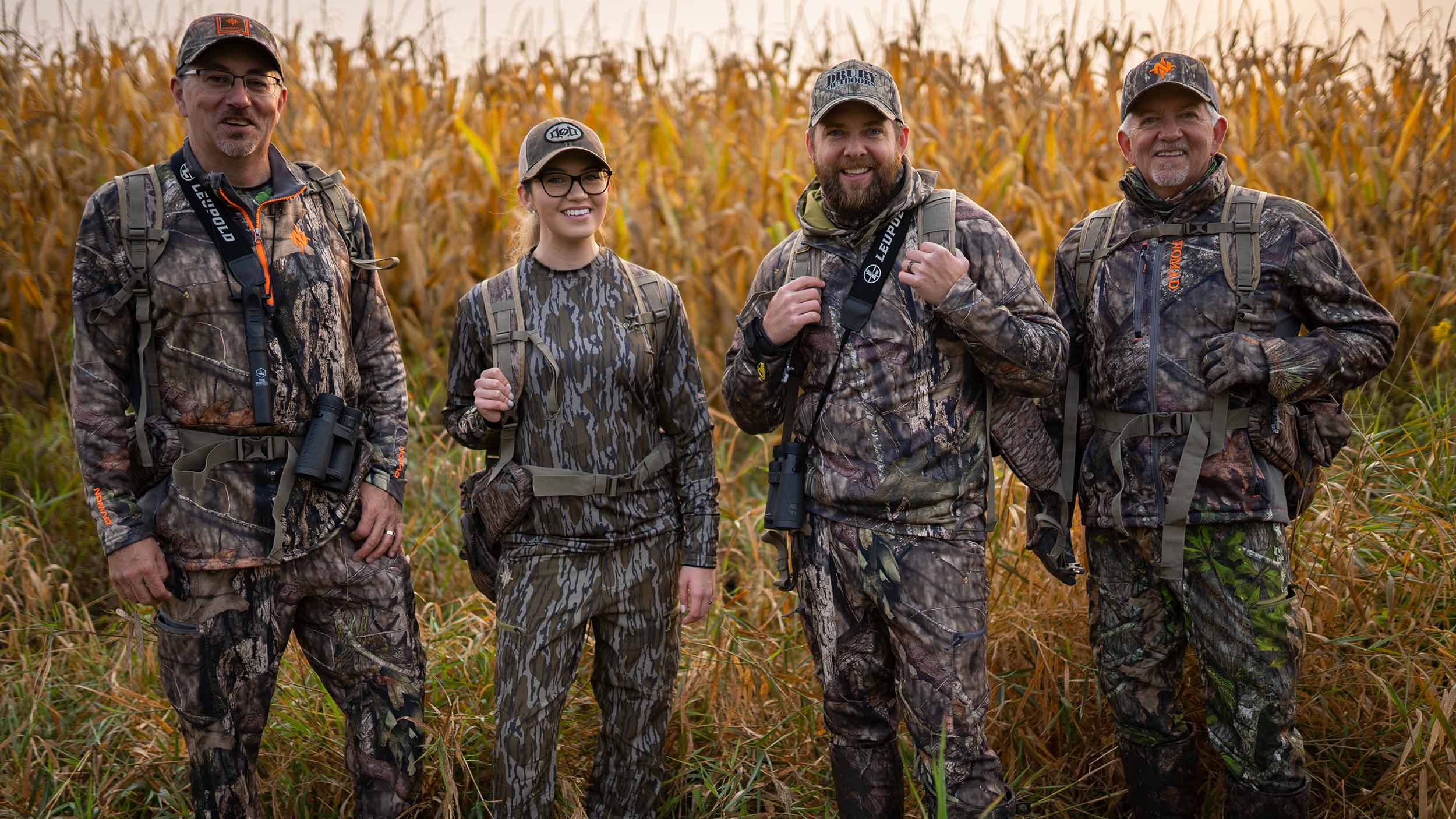 Four members of the Drury family posing outdoors in camo with the turkey they caught in a hunt.