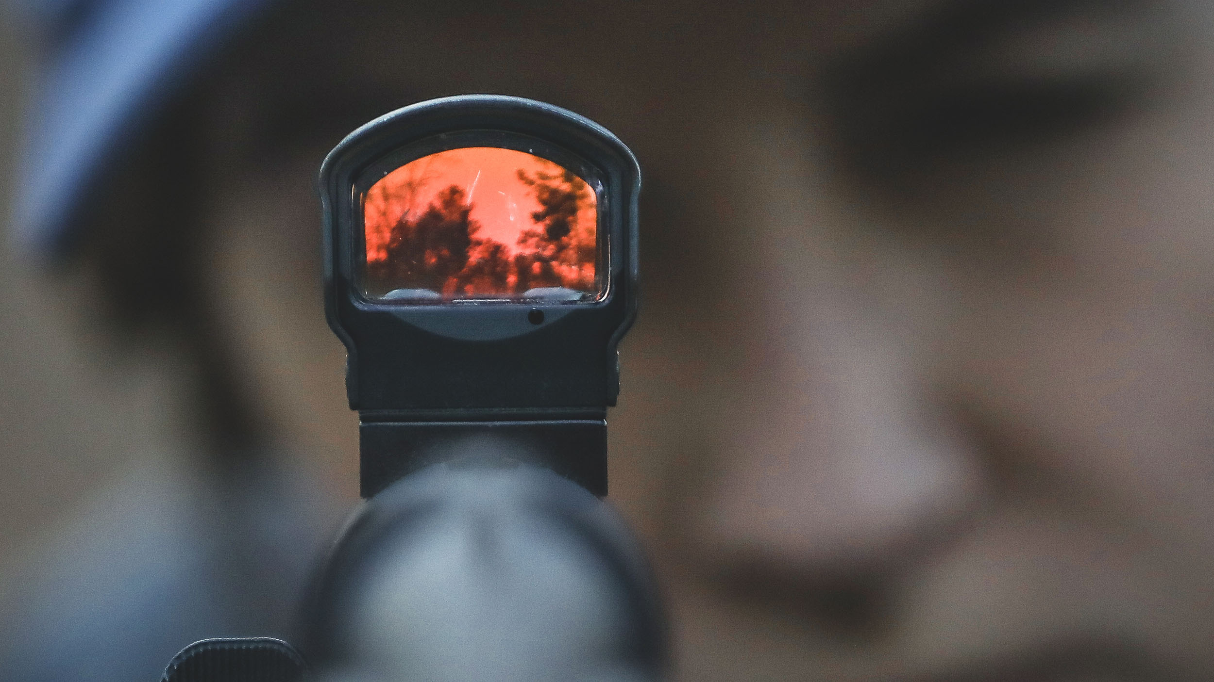 Close-up image of someone looking down the barrel of a shotgun with the Leupold DeltaPoint Pro mounted on its top.