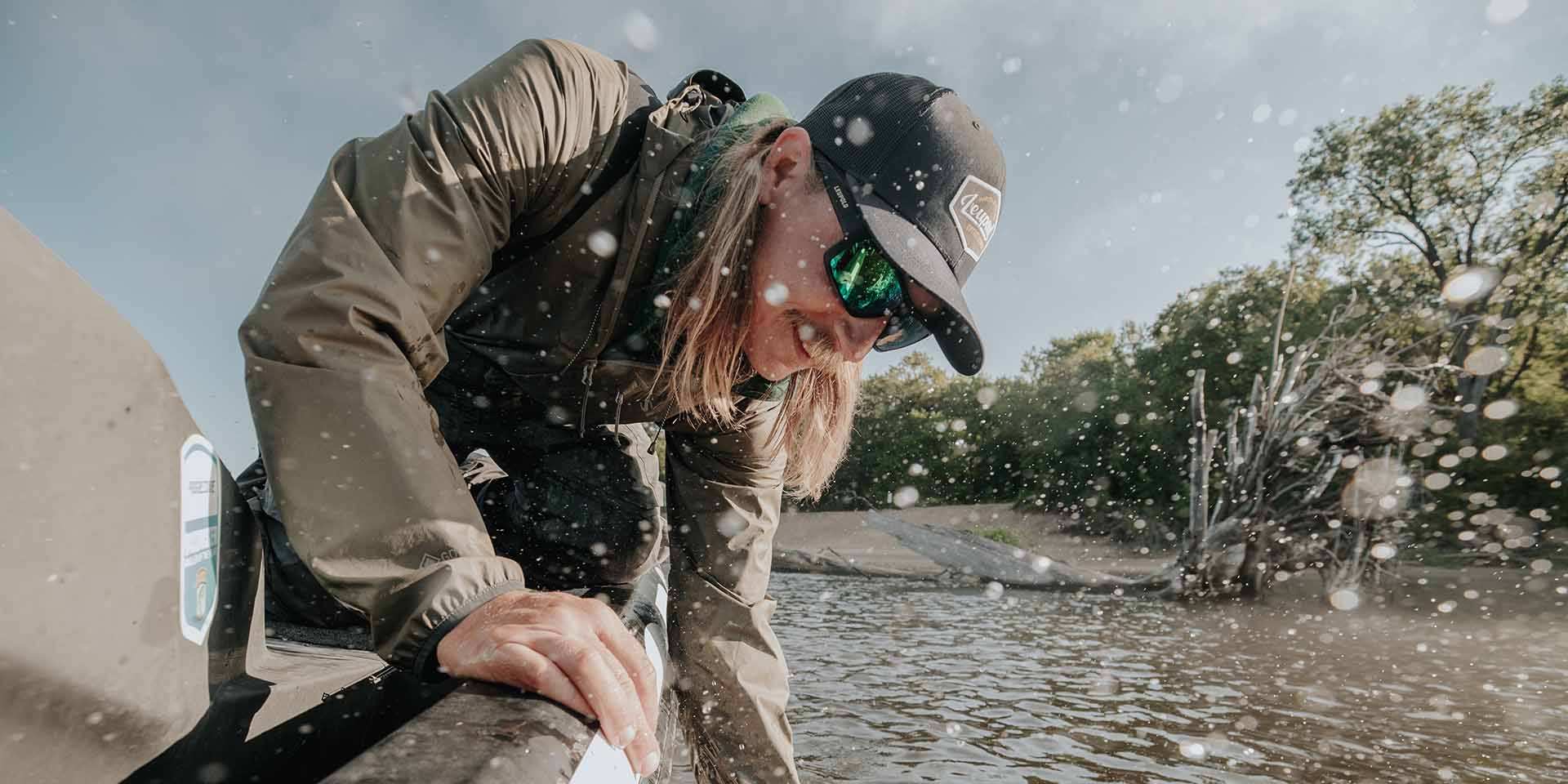 Fisherman on his boat pulling a fish out of water while wearing Leupold Performance Eyewear.