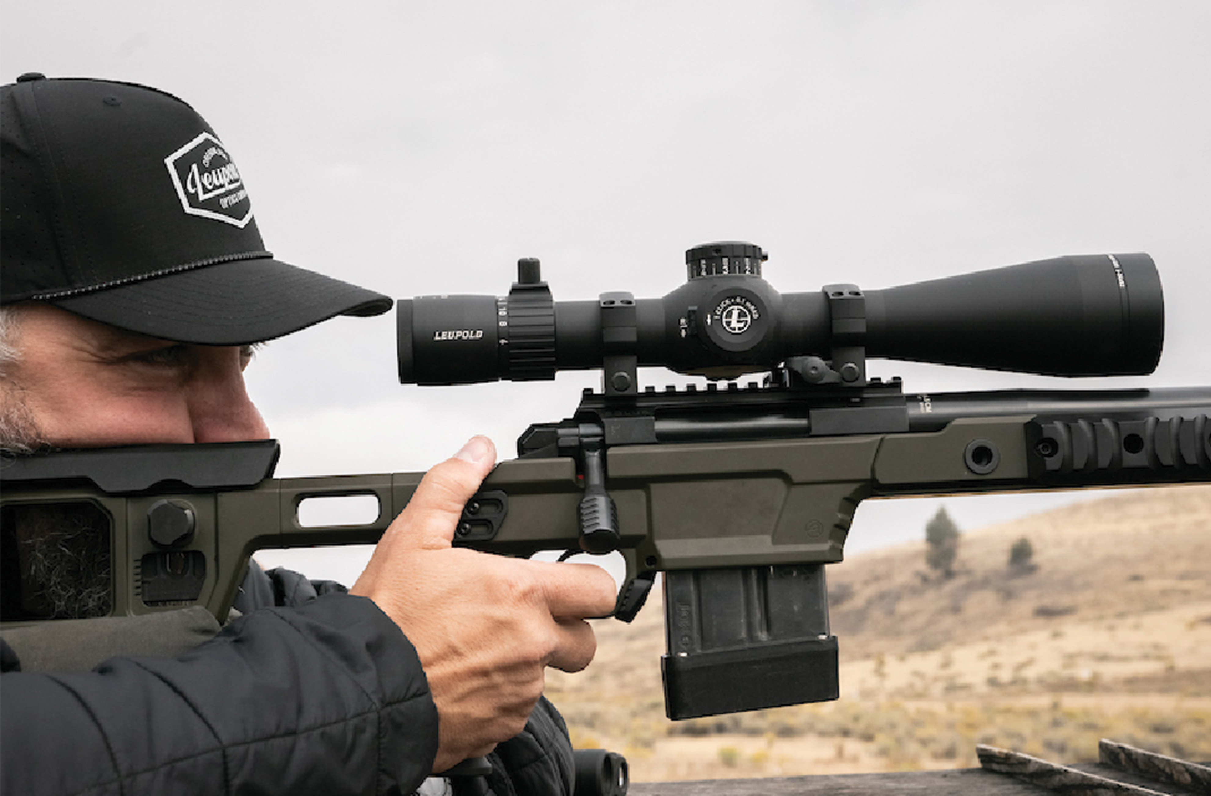 Man taking aim and looking through a Leupold Mark 4HD riflescope.