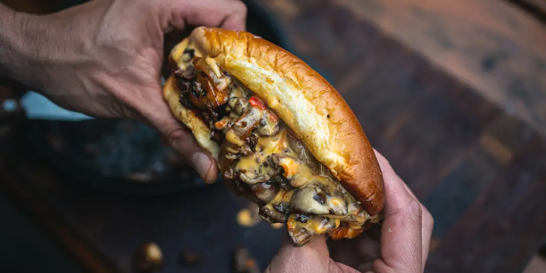 Man holding a Philly Cheesteak Sandwic made of venison meat