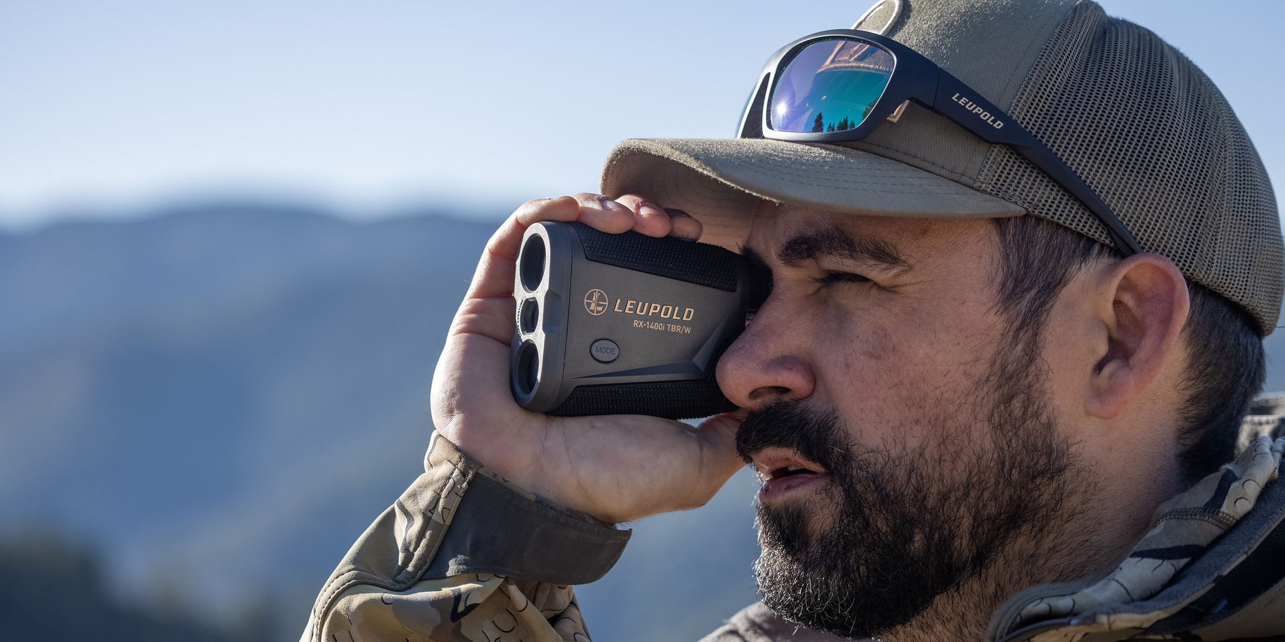 Product image of the new RX-1400i Leupold Rangefinder being held. Upclose image of rangefinder and model's face.