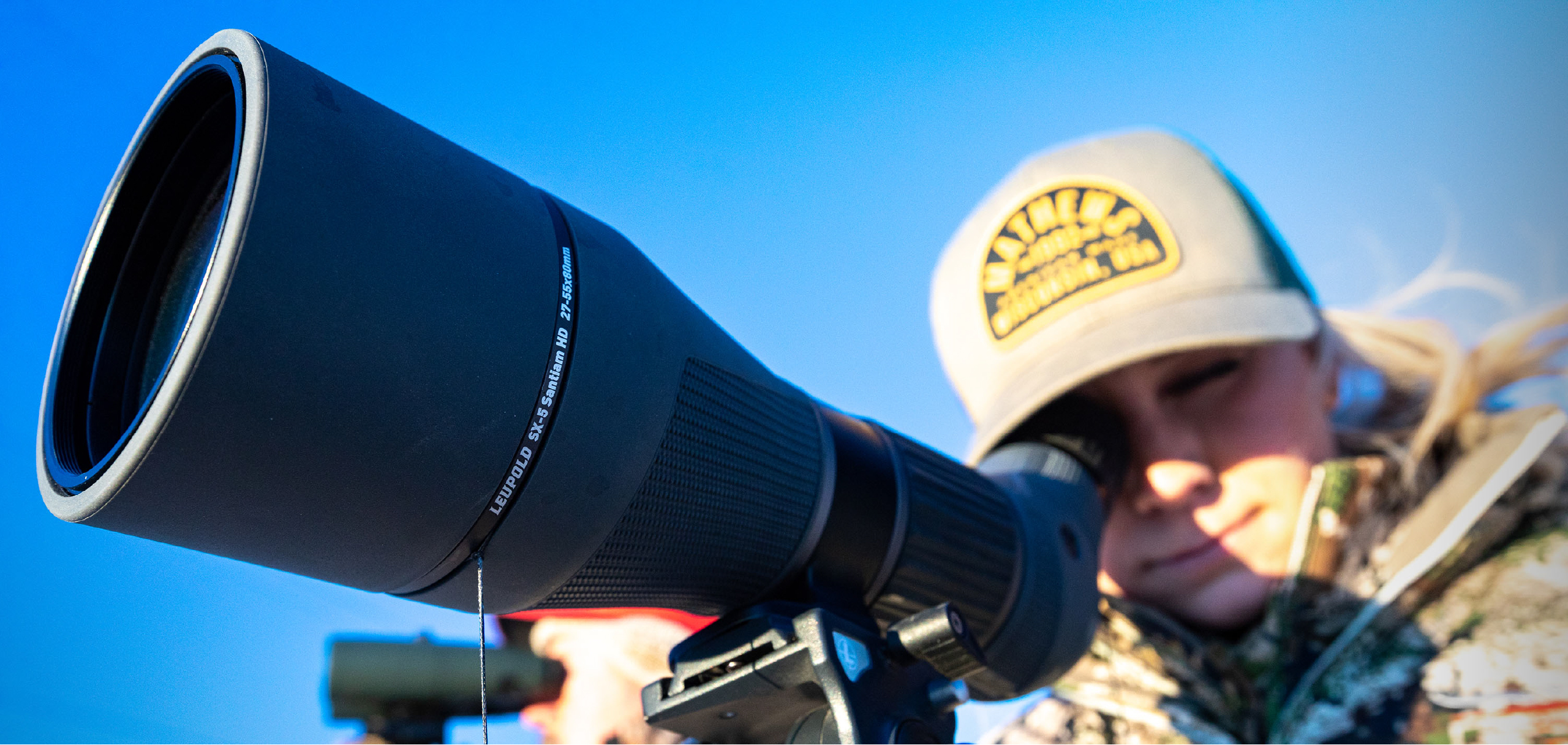 hunter wearing camouflage and hat glassing with leupold binoculars