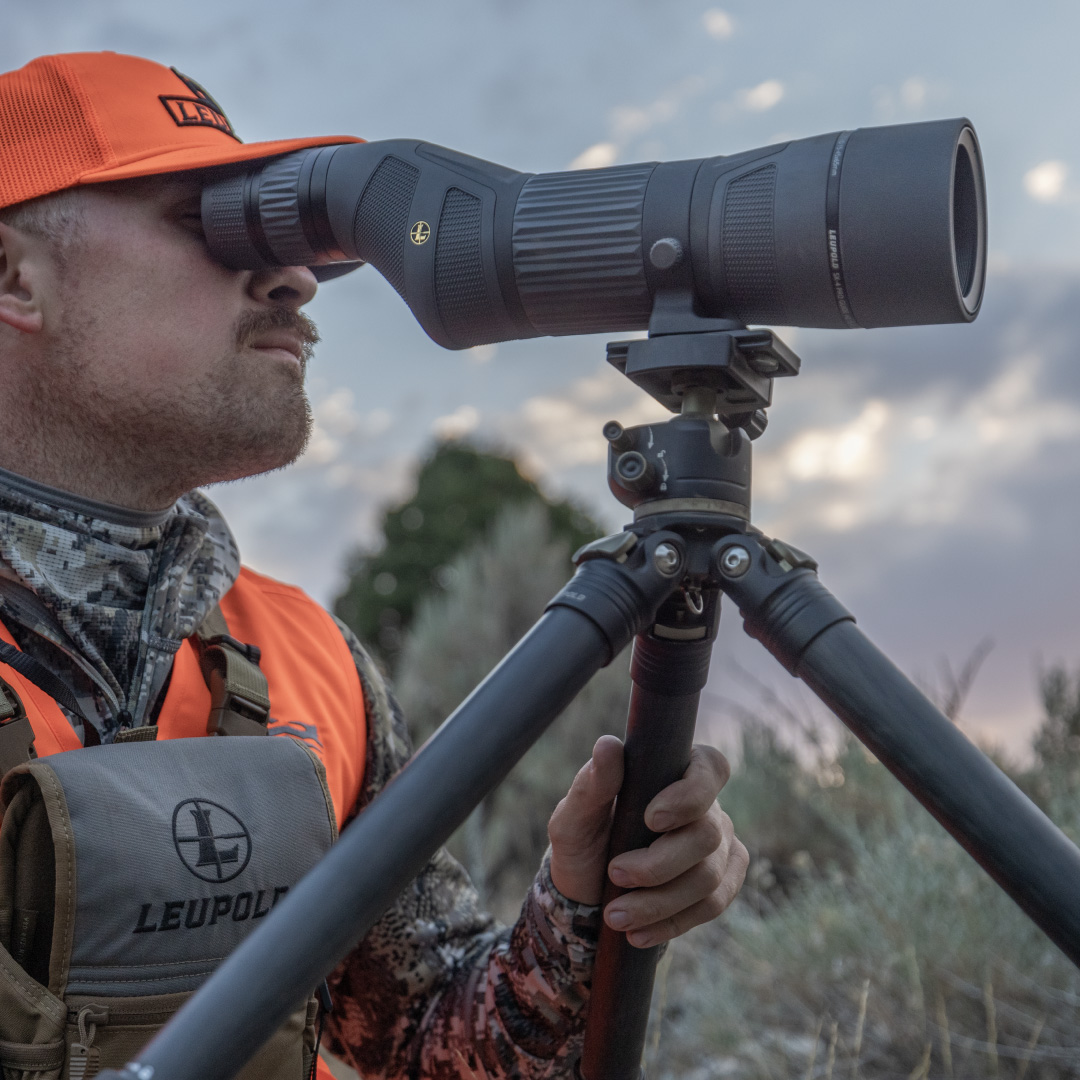 hunter wearing camouflage and hat glassing with leupold binoculars